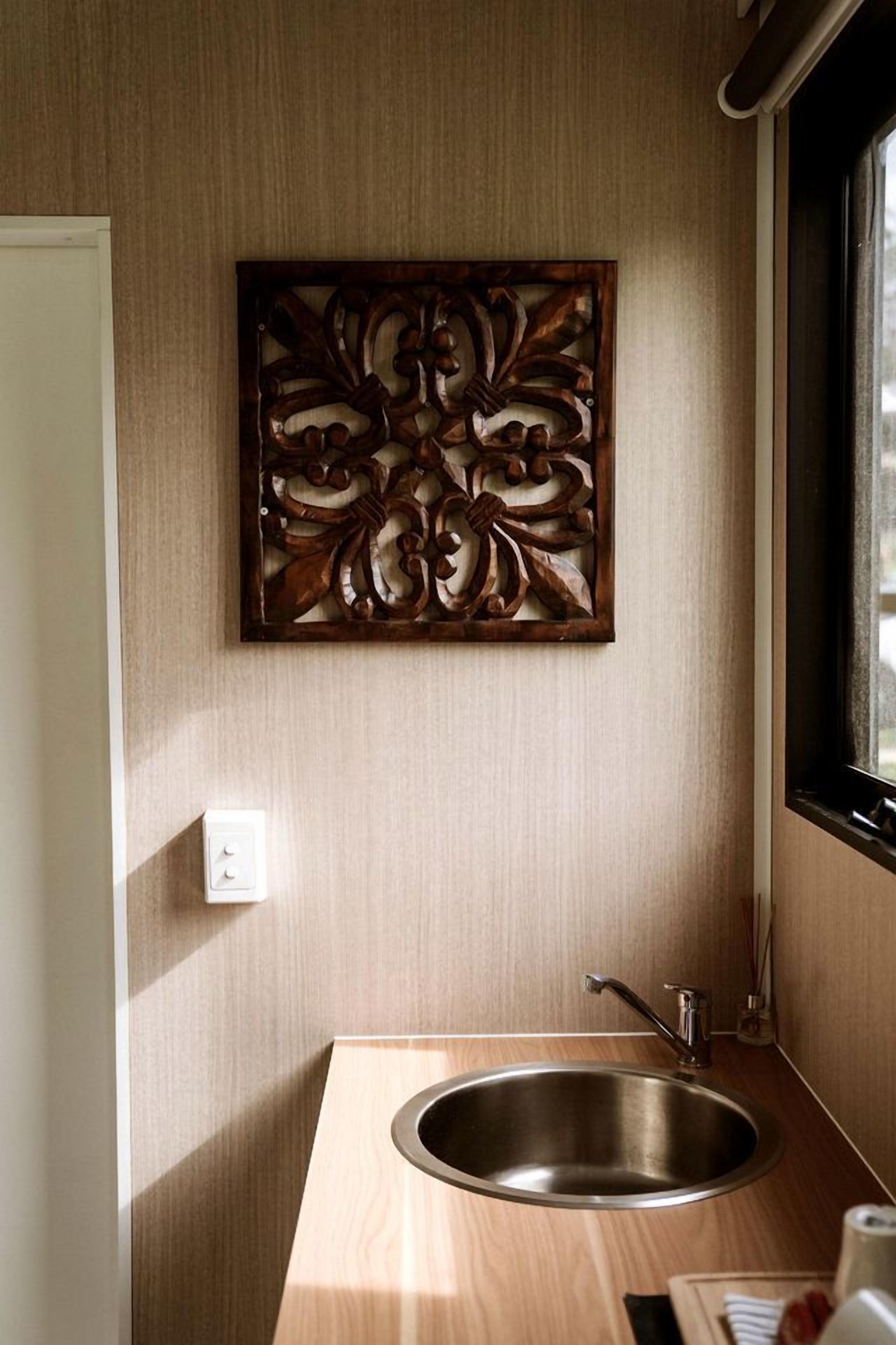 A small kitchen area with a wooden countertop, a stainless steel sink, and a decorative wall panel.