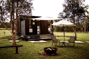 Une petite cabane en bois avec un porche, des sièges d’extérieur et un foyer.
