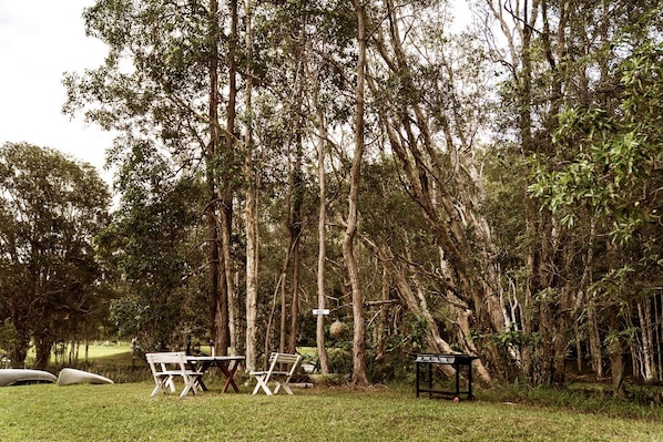 Un'area picnic con tavolo e sedie, circondata da alberi alti.