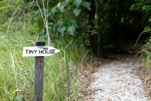 A wooden signpost with a white sign reading 'TINY HOUSE' pointing to the right.