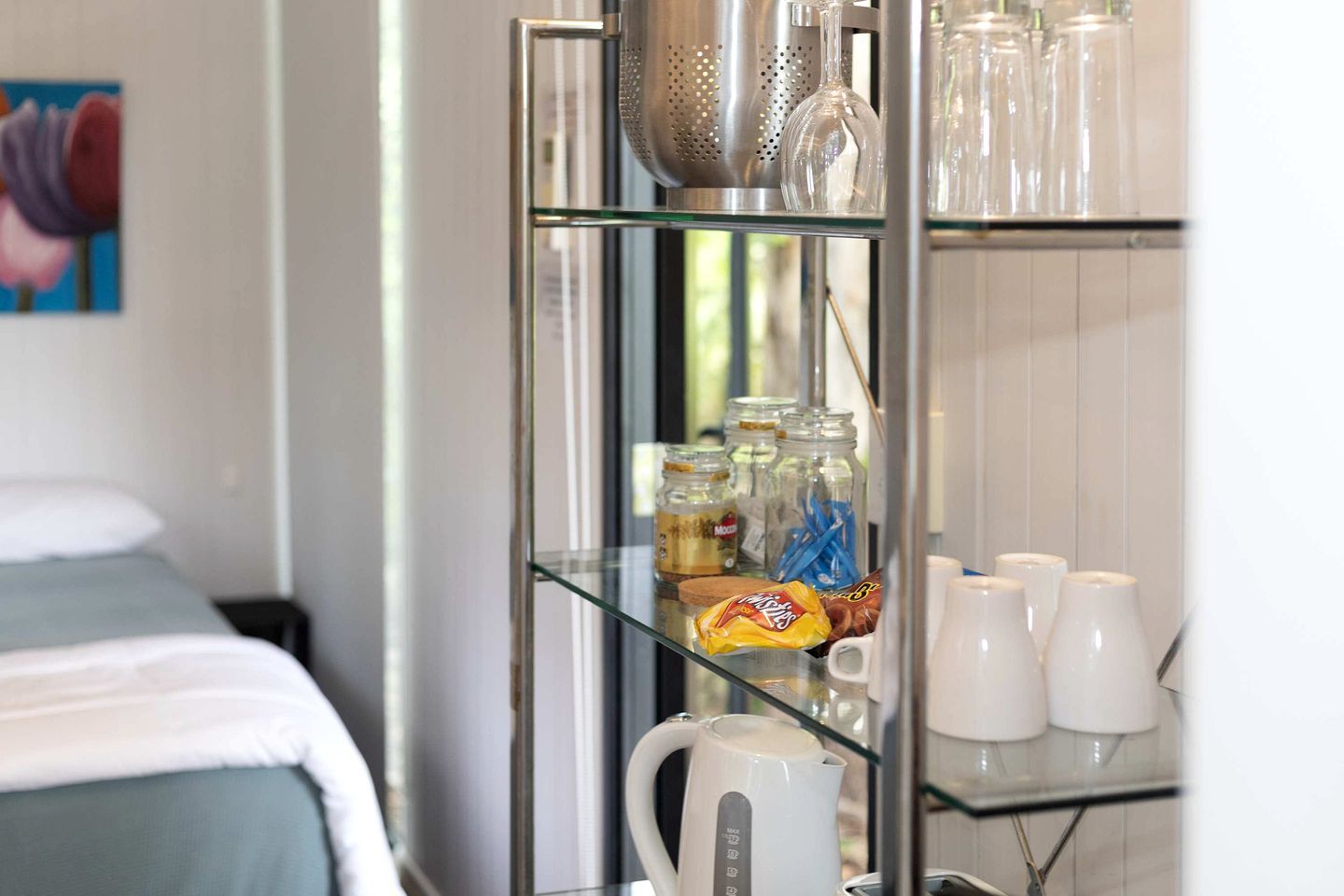 A kitchenette with a coffee maker, jars, and a bag of snacks.