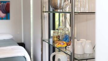 A kitchenette with a coffee maker, jars, and a bag of snacks.
