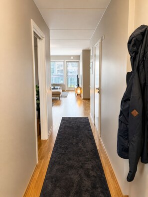 Ein Flur mit dunklem Teppich, Holzdielen und einem Mantel an der Wand.