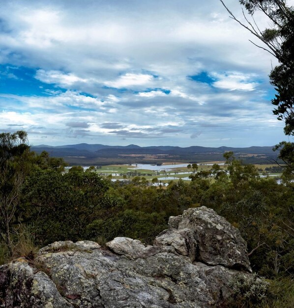 A natural landscape with a view of distant hills, a body of water, and a clear sky.