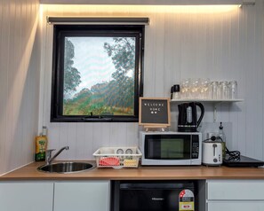 A compact kitchen with a sink, a microwave, a toaster, a coffee maker, and a small shelf with glasses. - Picturesque Secluded Tiny House in Bullahdelah, New South Wales (Bulahdelah)