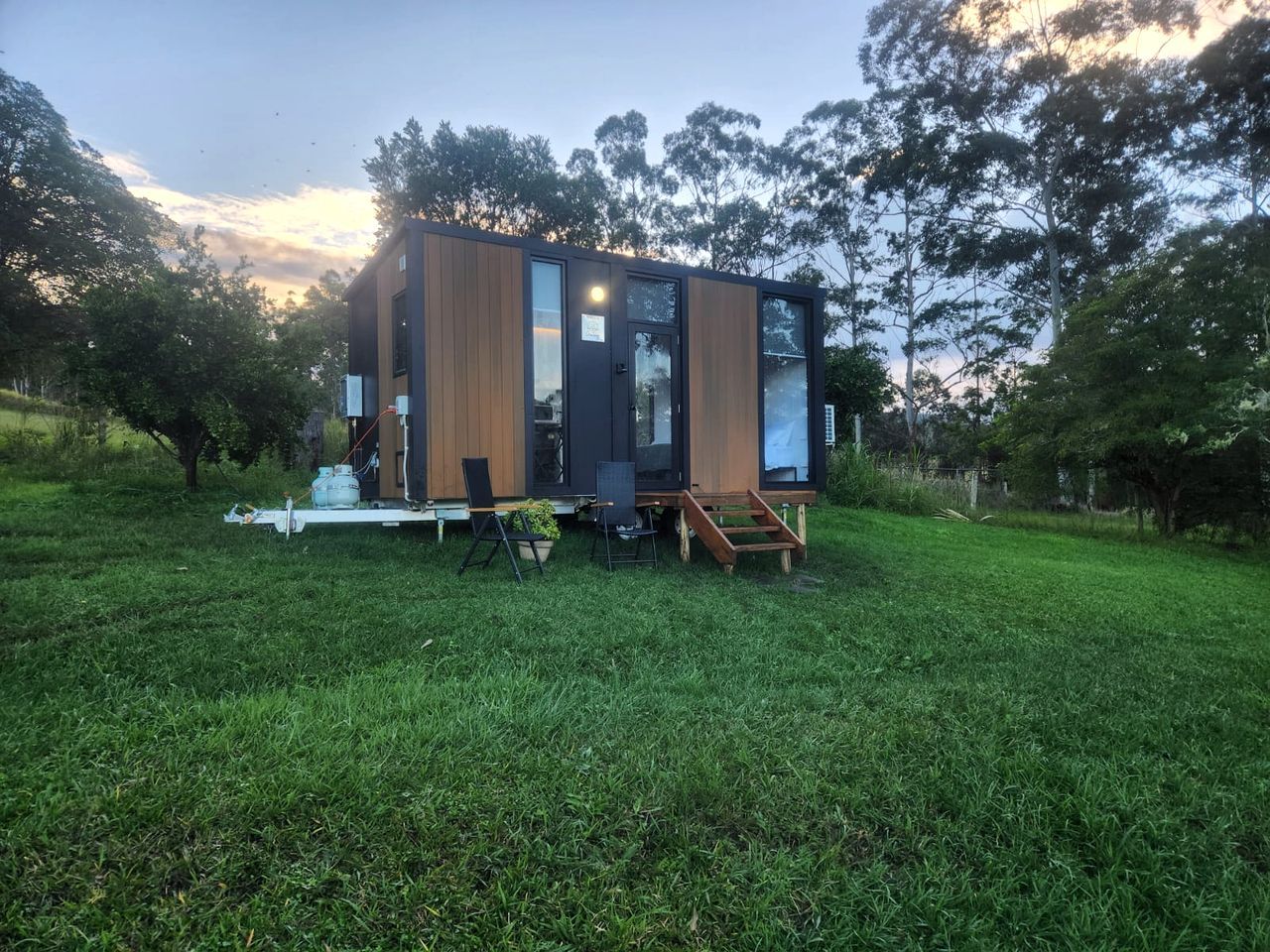 Un edificio moderno e compatto con tetto piatto, ampie finestre e un patio in legno.