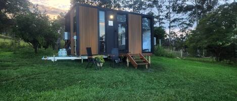 Un edificio moderno e compatto con tetto piatto, ampie finestre e un patio in legno.