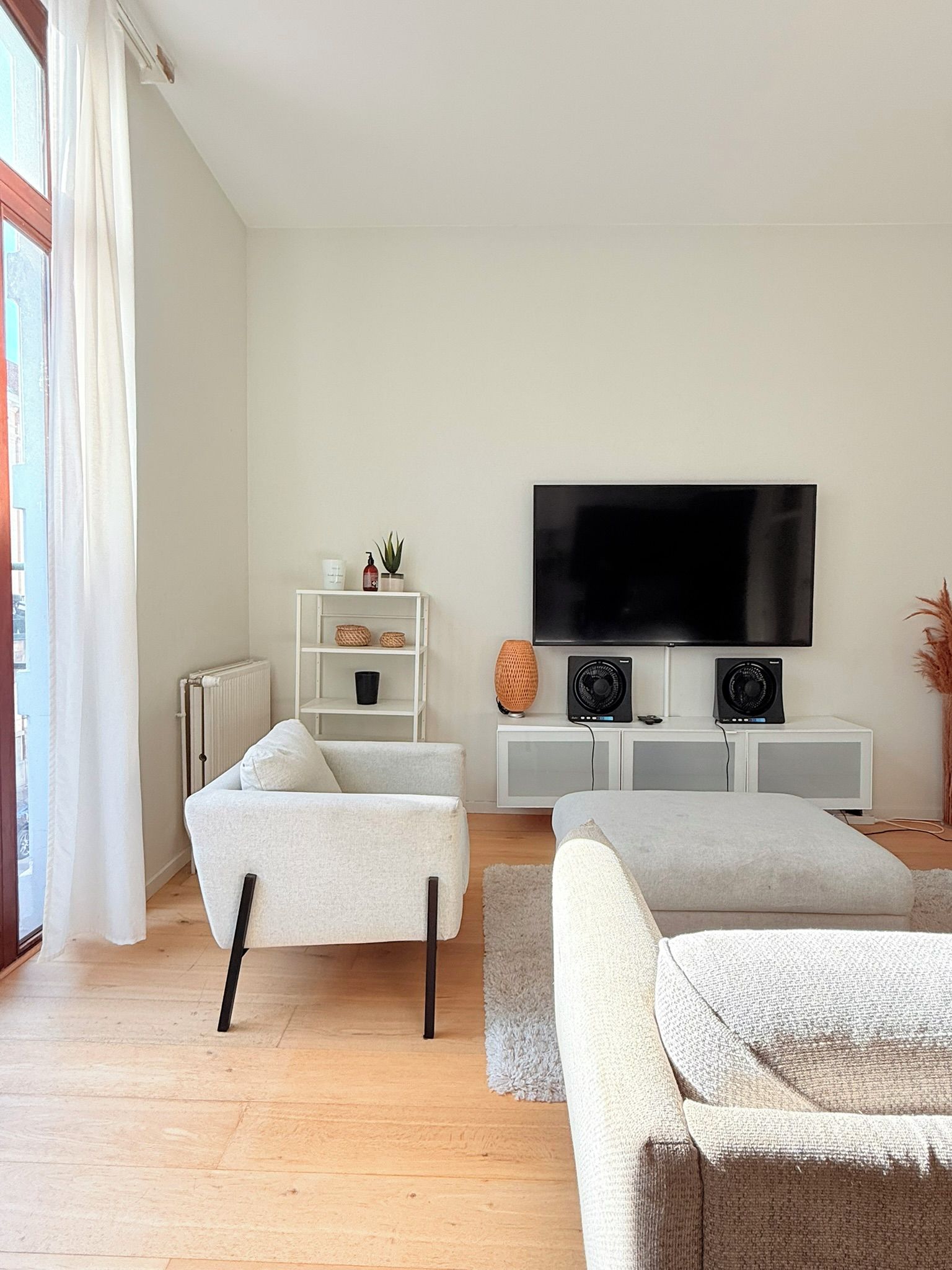 Una sala moderna con un sofá, una televisión y una consola blanca.