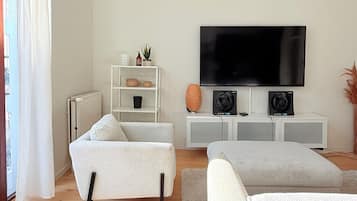 Una sala moderna con un sofá, una televisión y una consola blanca.