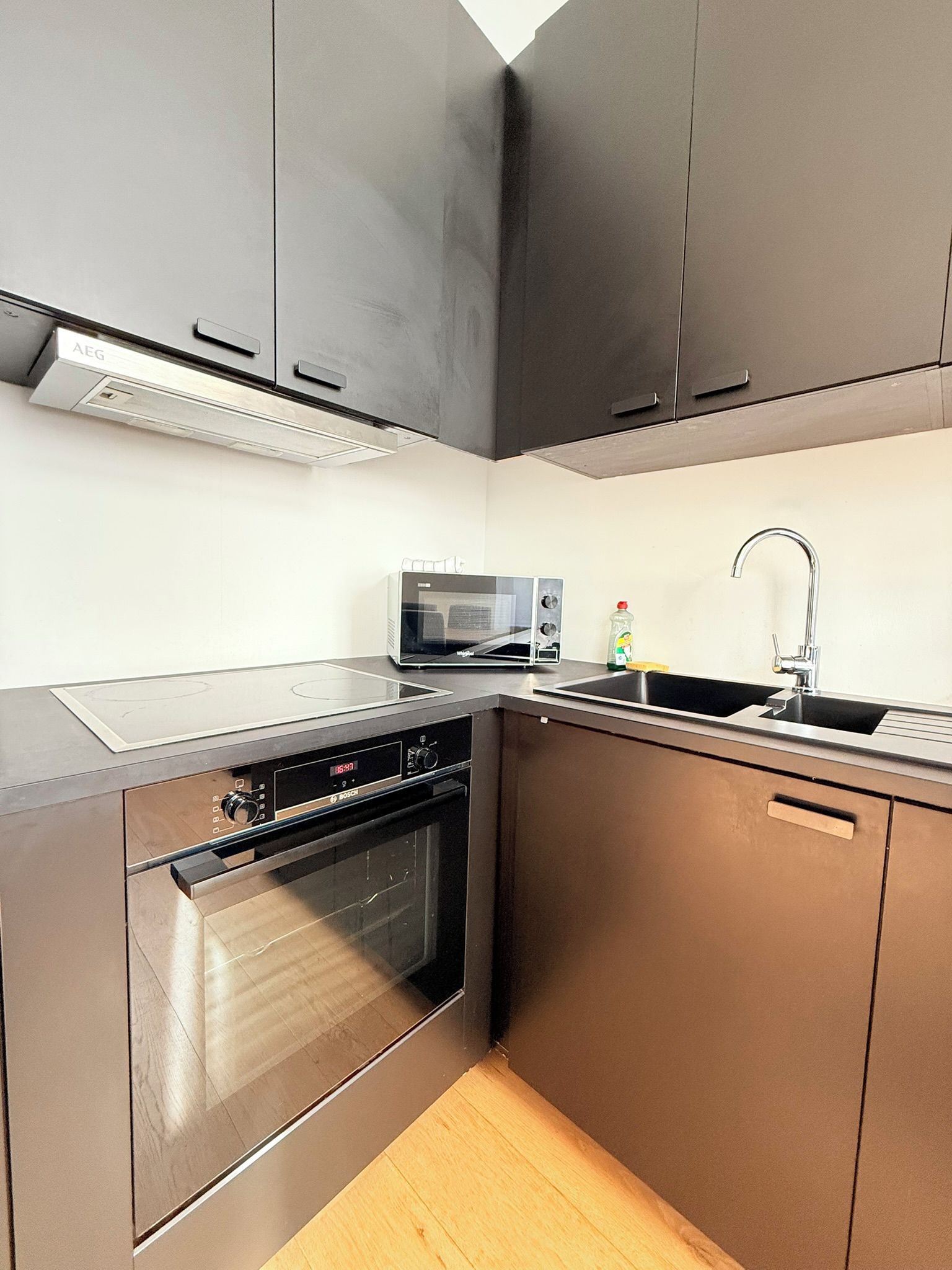 Una cocina moderna con electrodomésticos de acero inoxidable, microondas y un lavamanos.