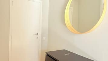 Una habitación con una puerta blanca, un aparador negro y un espejo redondo en la pared.