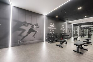 Ein Fitnessstudio mit Spiegelwand, Gewichtsständern und motivierenden Sprüchen.