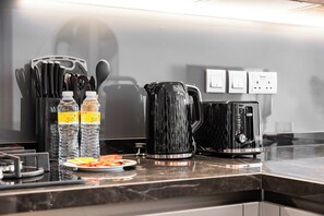 Eine Küchenarbeitsplatte mit einer Kaffeemaschine, Wasserflaschen und einem Teller Essen.