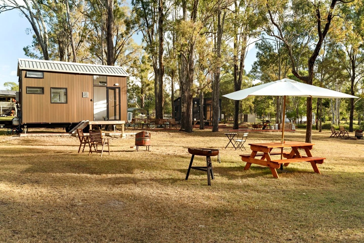 Um camping com cabana de madeira, mesas de piquenique e área de estar ao ar livre.
