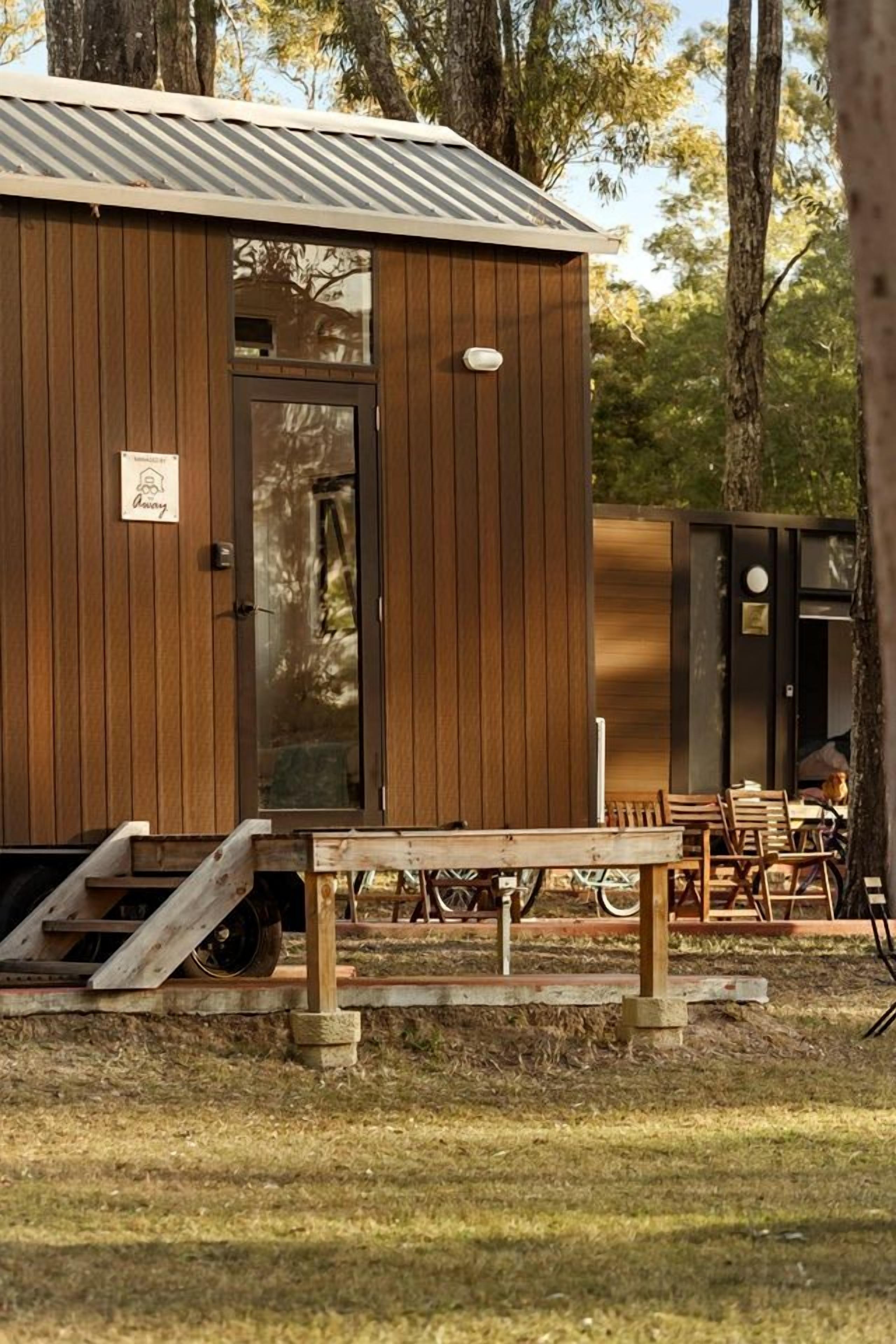 Eine Holzhütte mit Tür, einer kleinen Veranda mit Bank und Tisch.