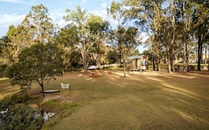 A grassy outdoor area with a small cabin, picnic tables, and a white chair.