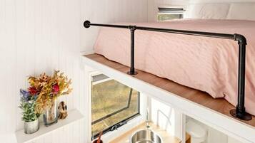 A compact, well-lit room with a bunk bed, a small kitchenette, and a window providing natural light.