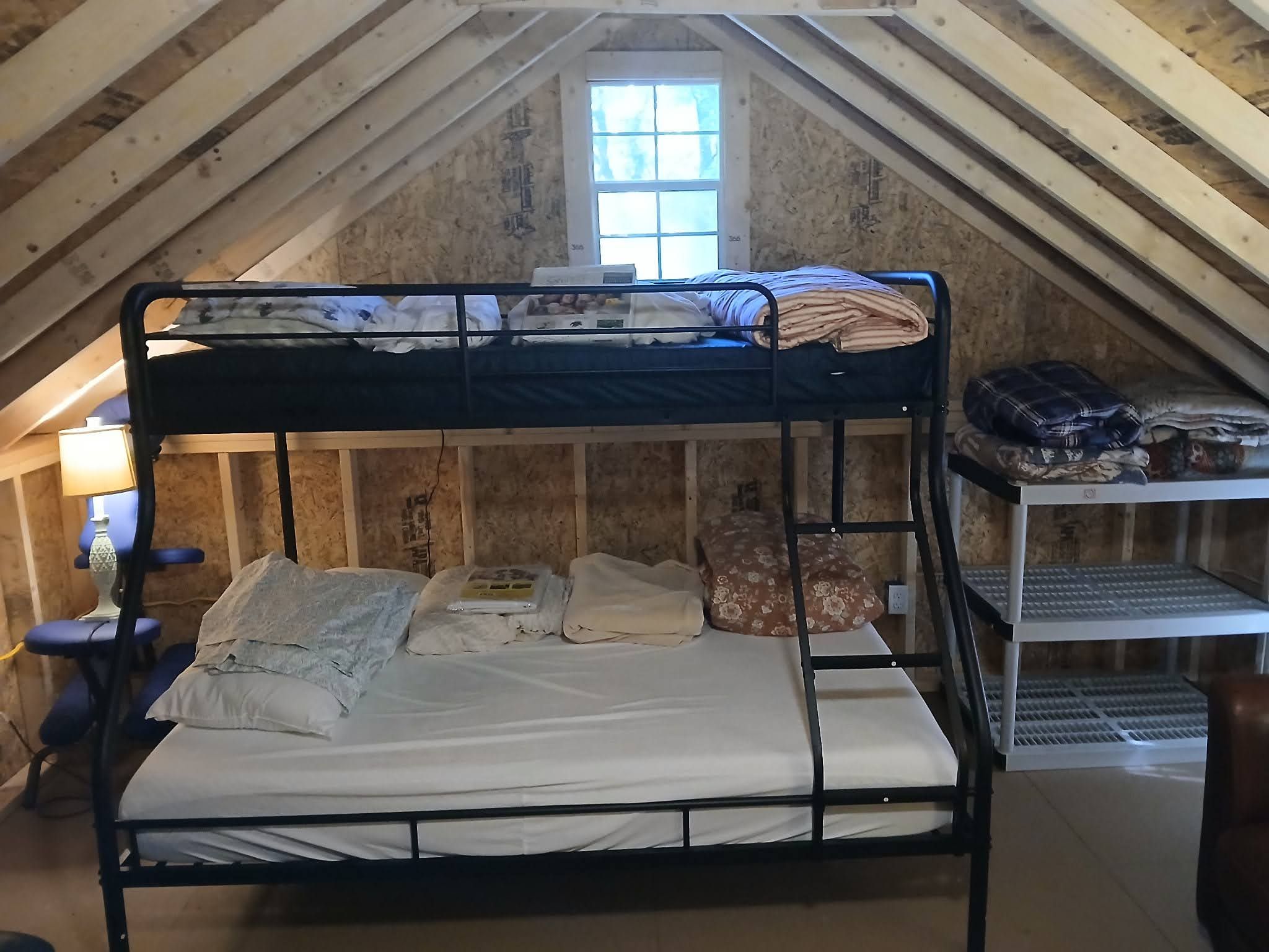A bunk bed in a room with wooden walls and a window.
