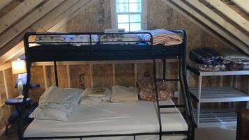 A bunk bed in a room with wooden walls and a window.