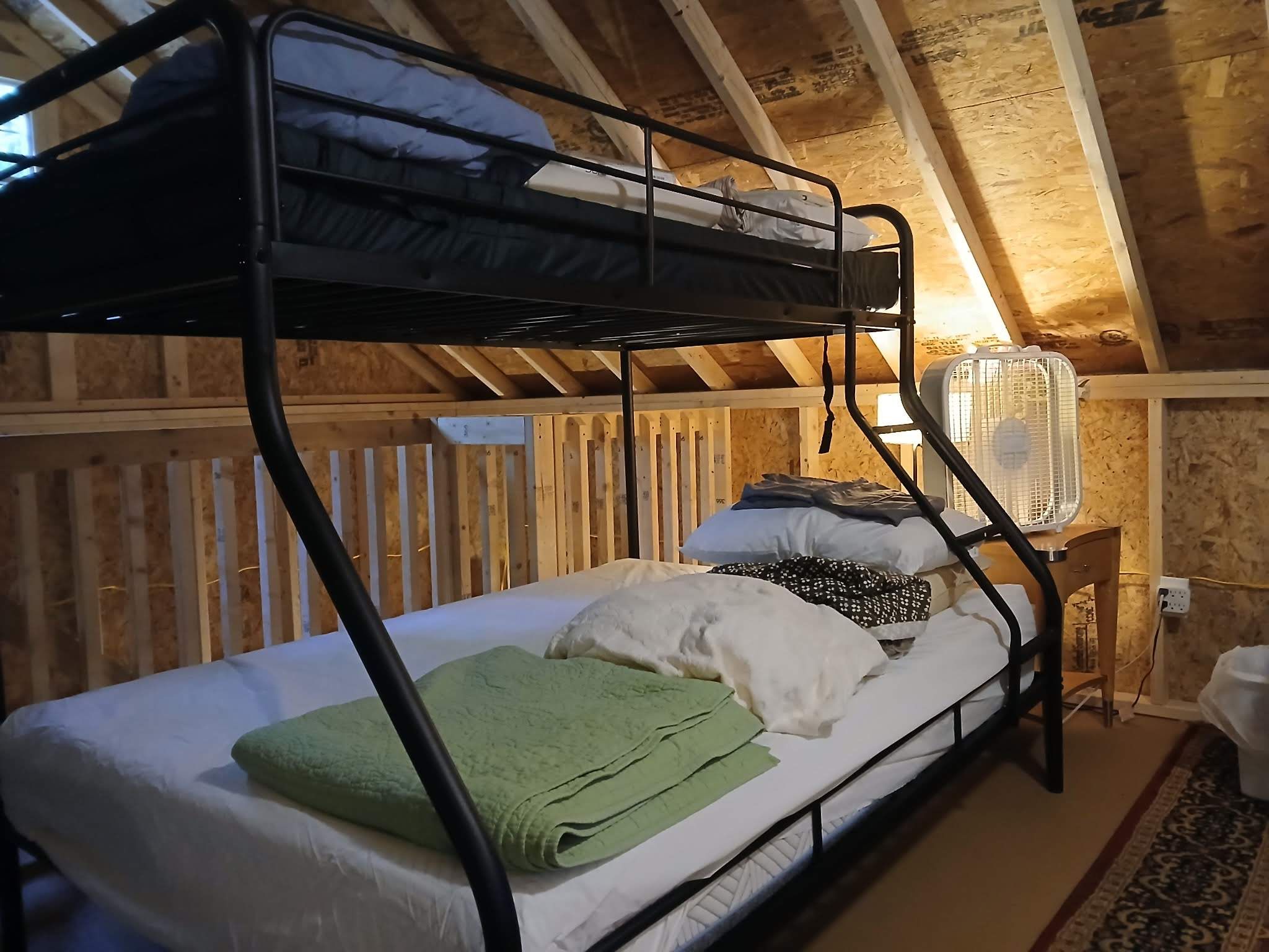 A bunk bed with a fan and a green towel.