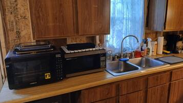 Una cocina con microondas, tostadora, pileta y armarios de madera.