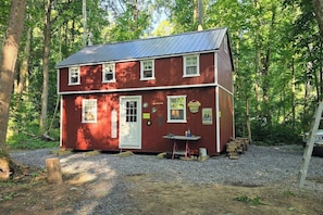 Un bâtiment rouge à deux étages, avec une allée gravillonnée, entouré d’arbres.