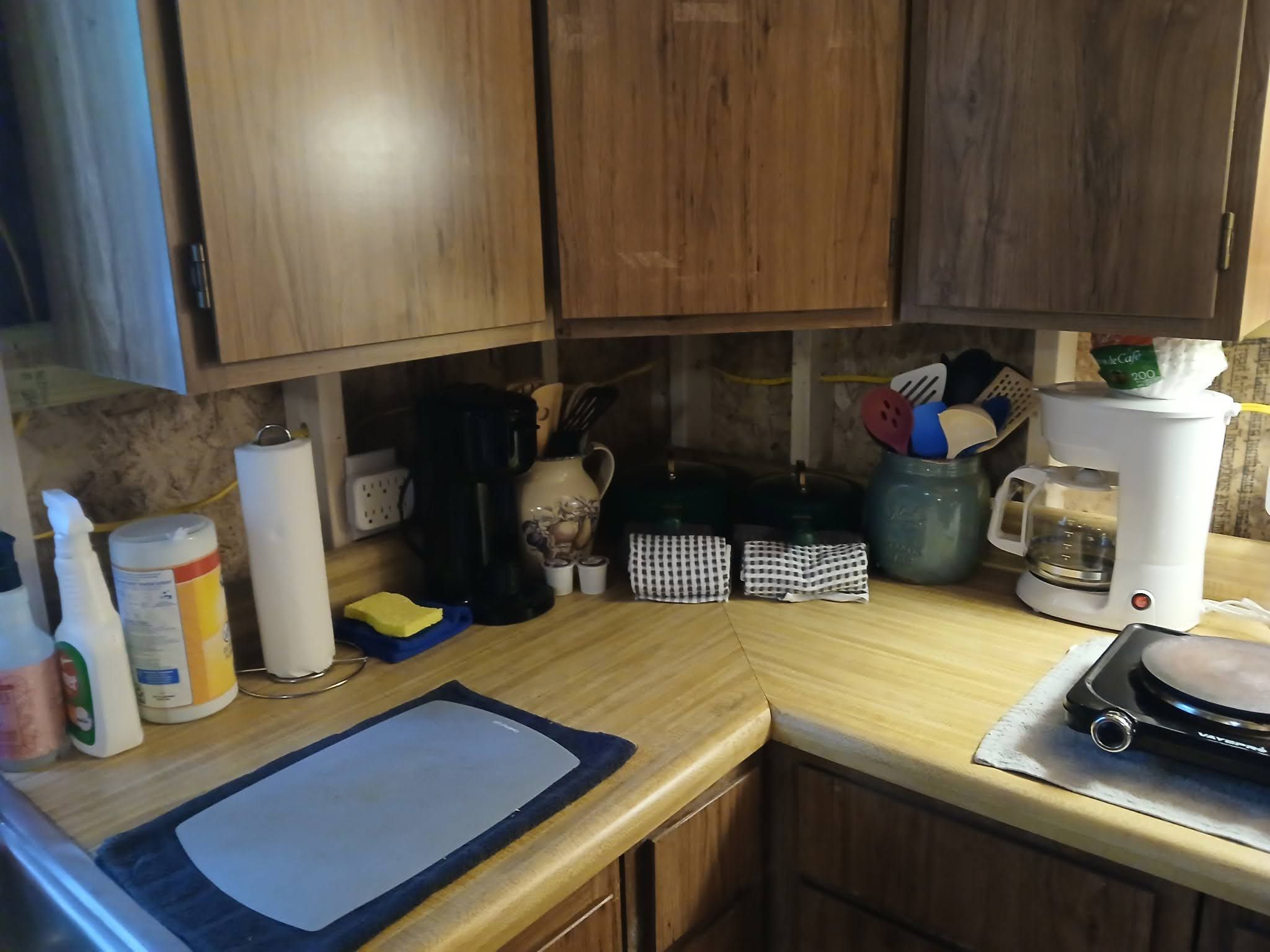Une cuisine dotée de meubles de rangement en bois, d’une machine à café, d’une bouilloire et de divers ustensiles de cuisine.