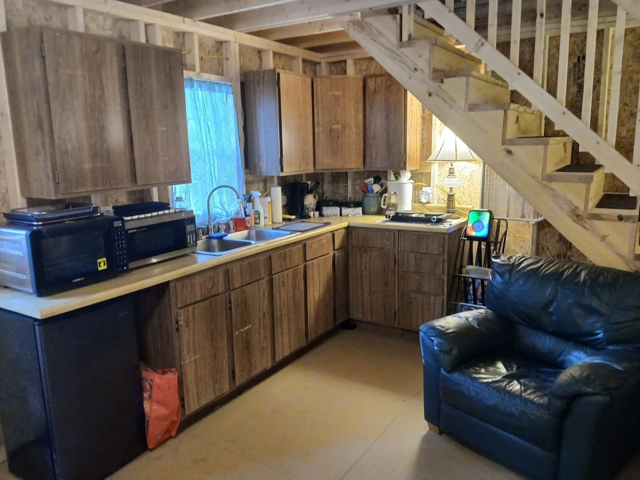 Una cucina con mobili in legno, un forno a microonde, un lavello e un divano in pelle nera.