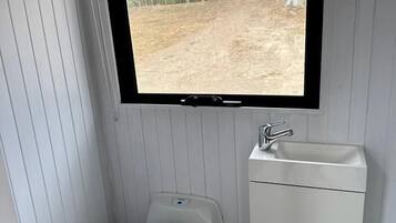 A small bathroom with a toilet, a sink, and a window.