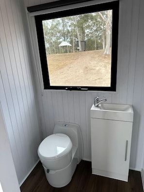 Un baño pequeño con inodoro, lavamanos y ventana.