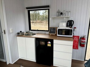 A compact kitchen with a sink, a microwave, a coffee maker, and a dishwasher.