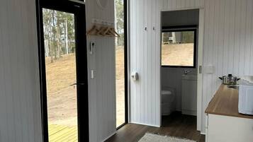 A room with a bed, a small kitchenette, and a bathroom.