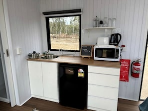 A compact kitchen with a sink, a microwave, a coffee maker, and a dishwasher.
