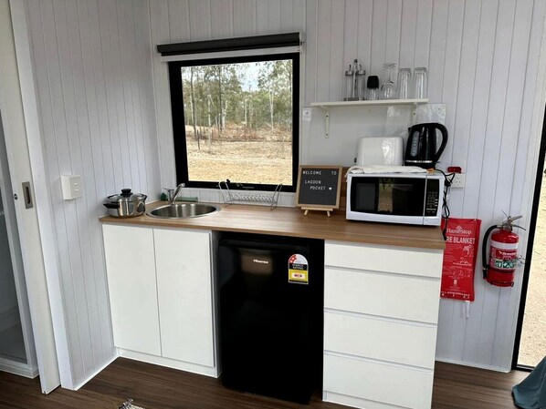 A compact kitchen with a sink, a microwave, a coffee maker, and a dishwasher.