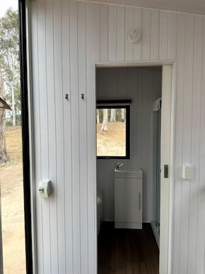 A compact bathroom with a window, a sink, and a mirror.