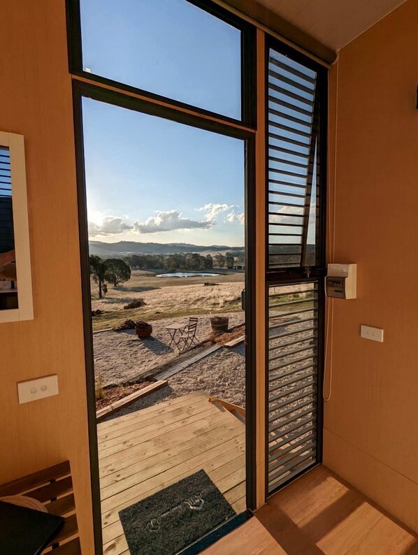 A room with a large sliding glass door leading to an outdoor area with a gravel path and a view of distant hills.
