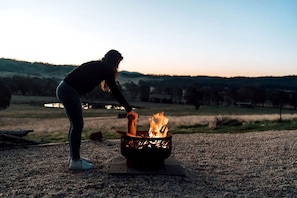 A person tending to a fire in a metal fire pit outdoors.
