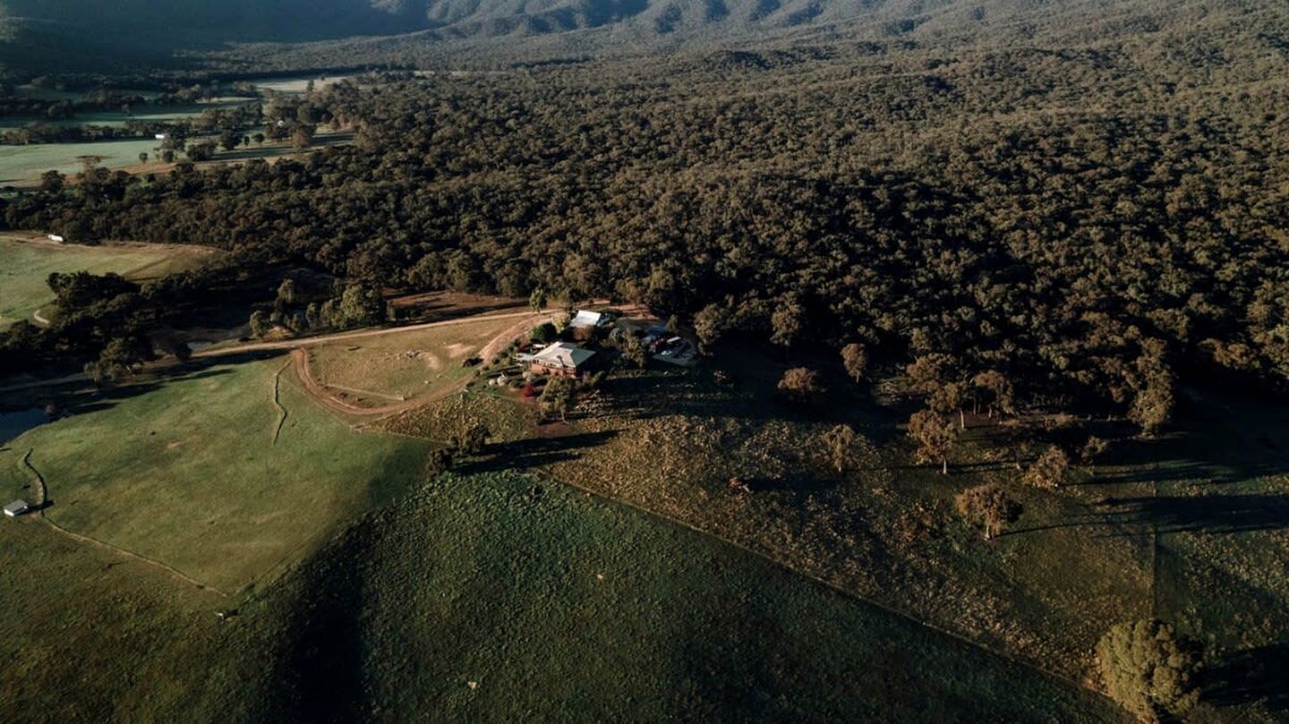 An aerial view of a rural area with a cluster of buildings surrounded by dense forest.