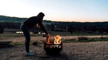 A person tending to a fire in a metal fire pit outdoors.