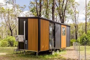 Casa móvel com porta deslizante, pequena janela e tomada lateral.