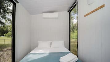 Quarto com uma cama, janela e ar-condicionado fixado na parede.