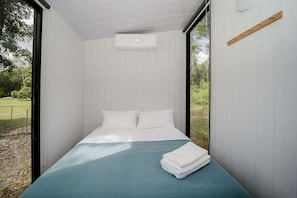 Quarto com uma cama, janela e ar-condicionado fixado na parede.