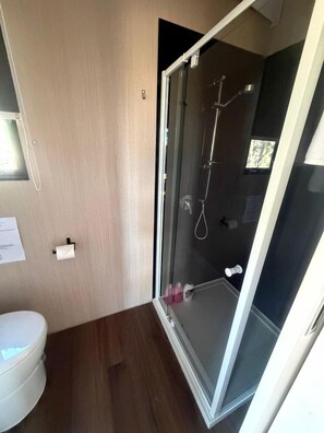 A modern bathroom with a glass-enclosed shower, a toilet, and a wooden floor. - Cozy Tiny House Retreat Near Grampians National Park in Stawell Victoria (Stawell)