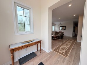 A hallway with a wooden bench, a patterned rug, and a dining area with a table and chairs.