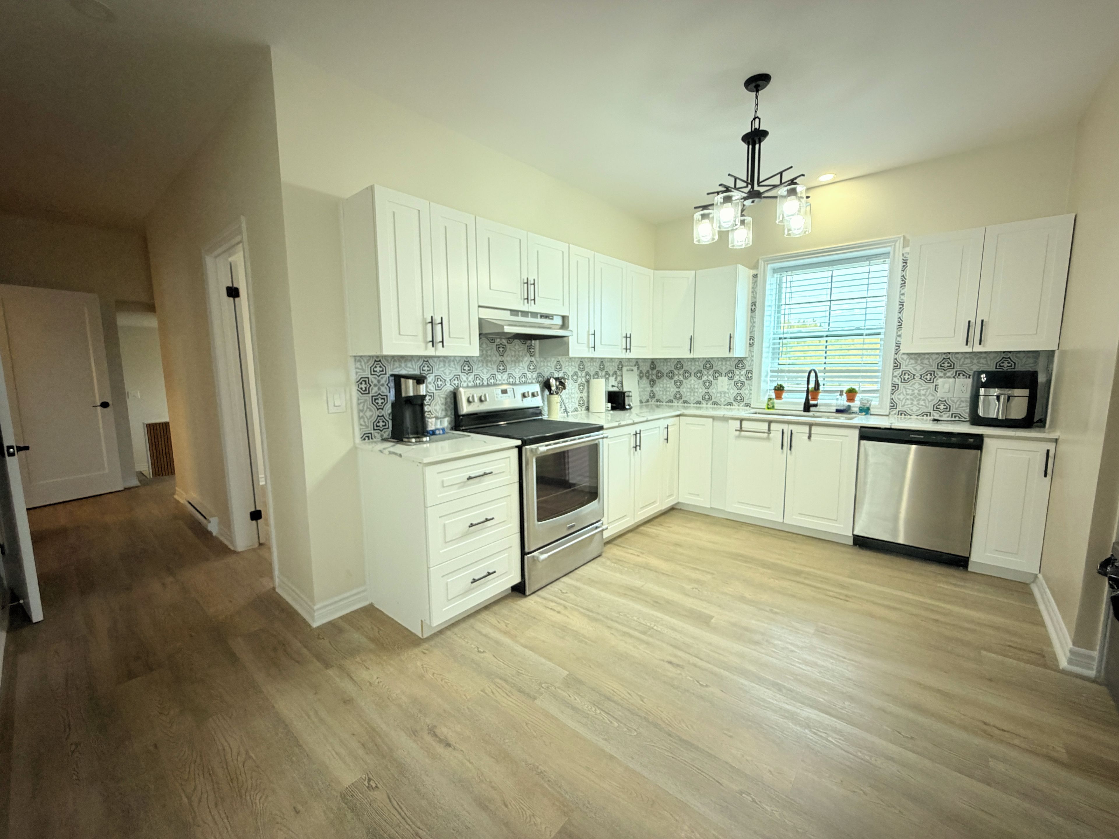 A modern kitchen with white cabinetry, a stainless steel range, and a built-in oven.