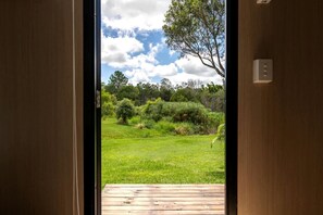 A wooden door leading to a grassy outdoor area with a wooden deck.