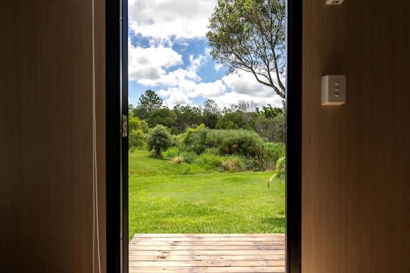 A wooden door leading to a grassy outdoor area with a wooden deck.