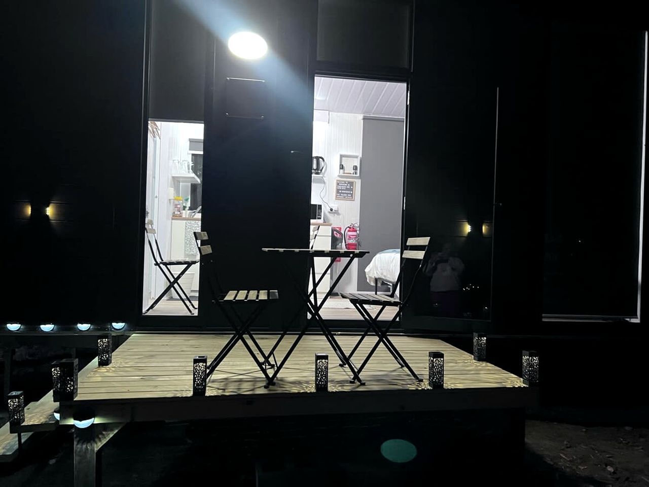 An outdoor stage with a table and chairs, surrounded by lanterns.