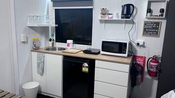 Une petite cuisine équipée d’un four à micro-ondes, d’un évier et d’un petit réfrigérateur.