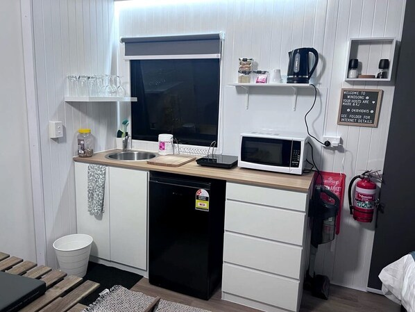 A compact kitchenette with a microwave, sink, and a small refrigerator.